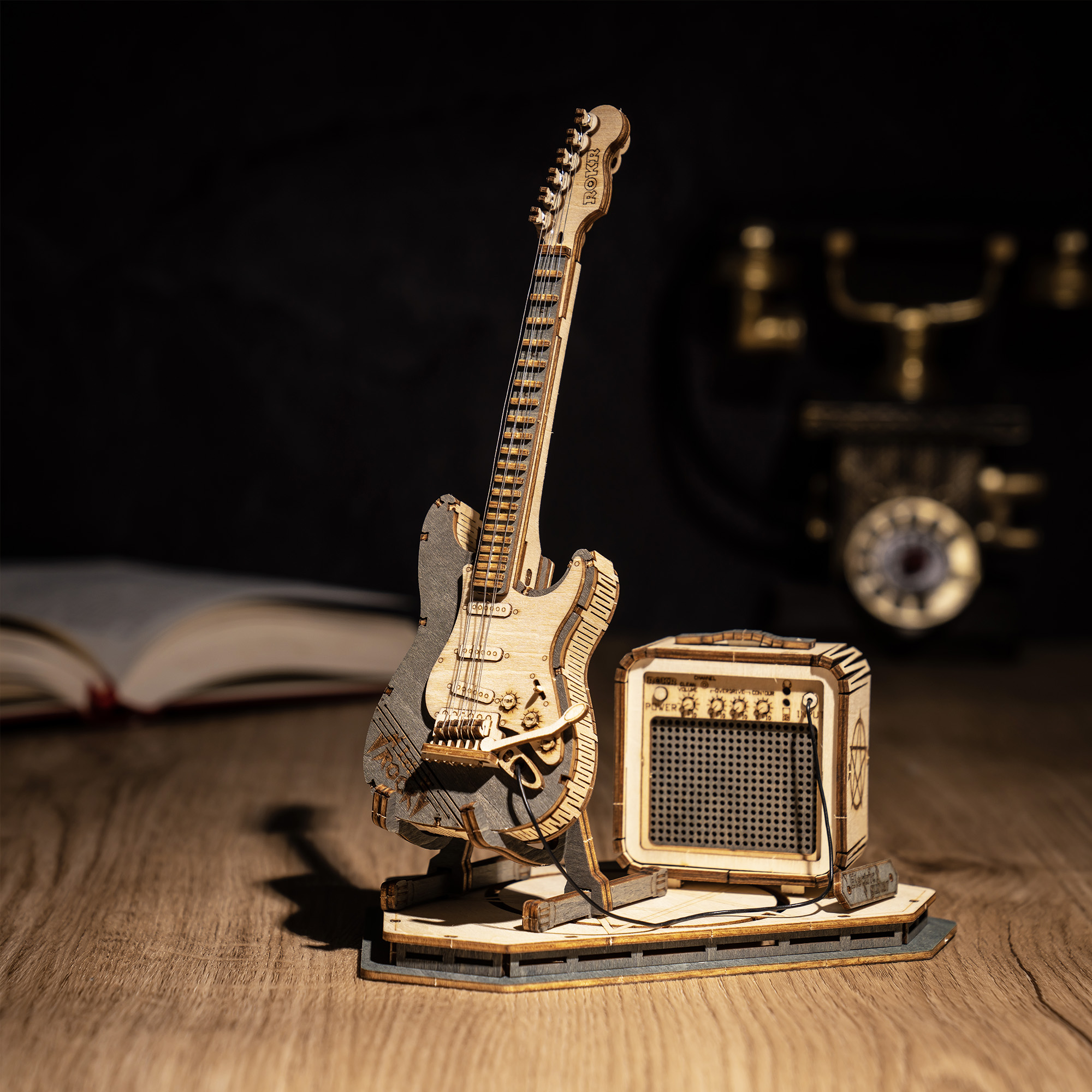 ROKR Guitare Électrique TG605K guitare en bois sur un bureau sombre à côté de l'amplificateur