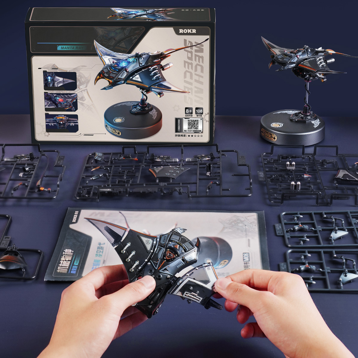 Manta Ray assembly scene with hands, package, and model parts